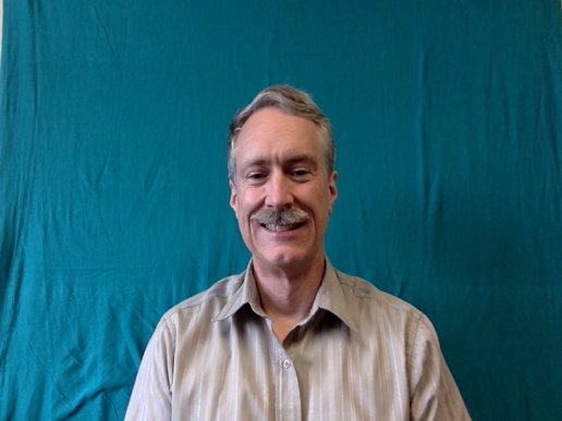 Prof Baldwin standing in front of a blue-green background