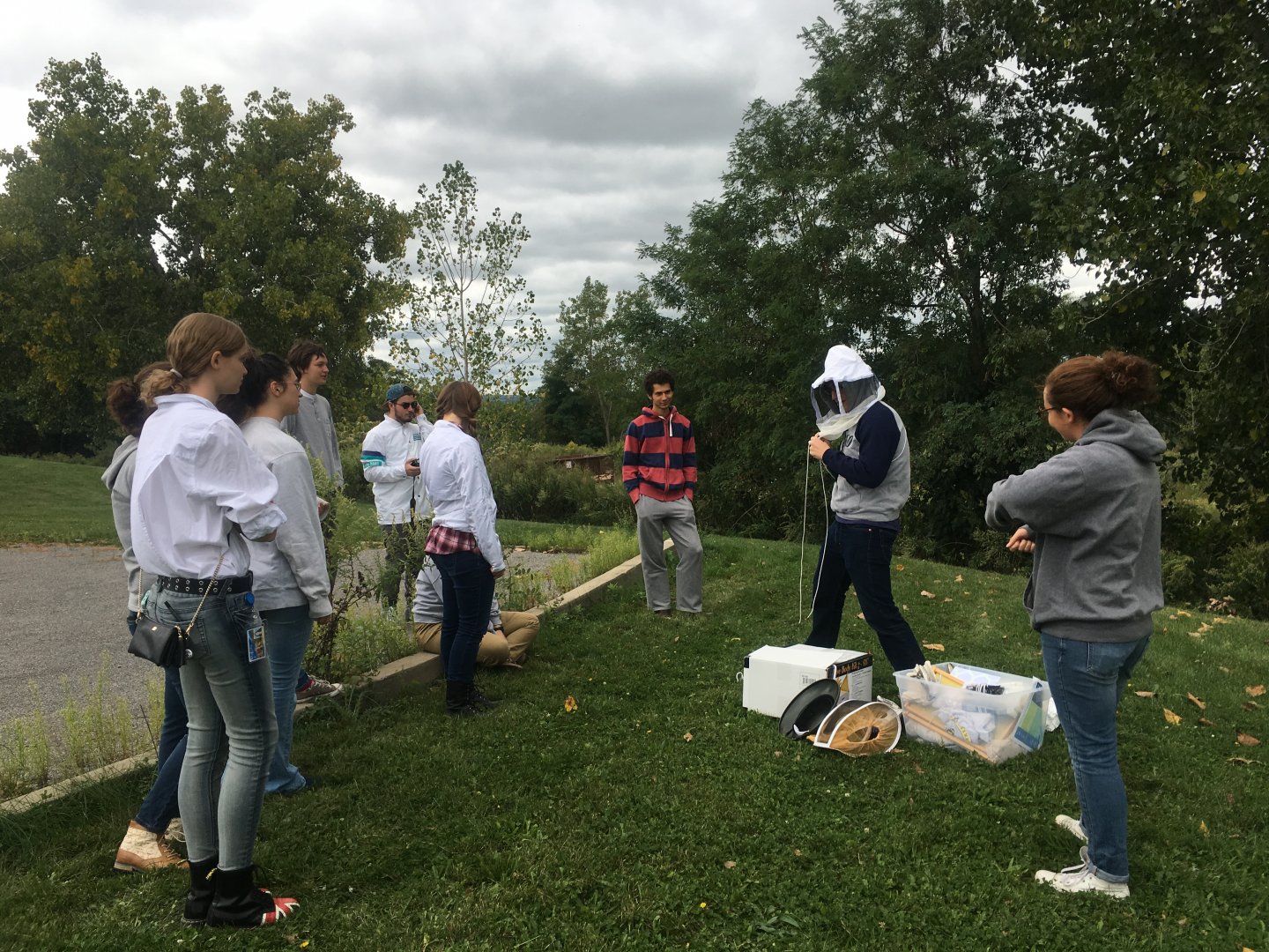 Group watching demonstrator put on a beekeeping veil