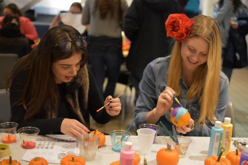 Salsa Con Salsa event, two students painting mini pumpkins