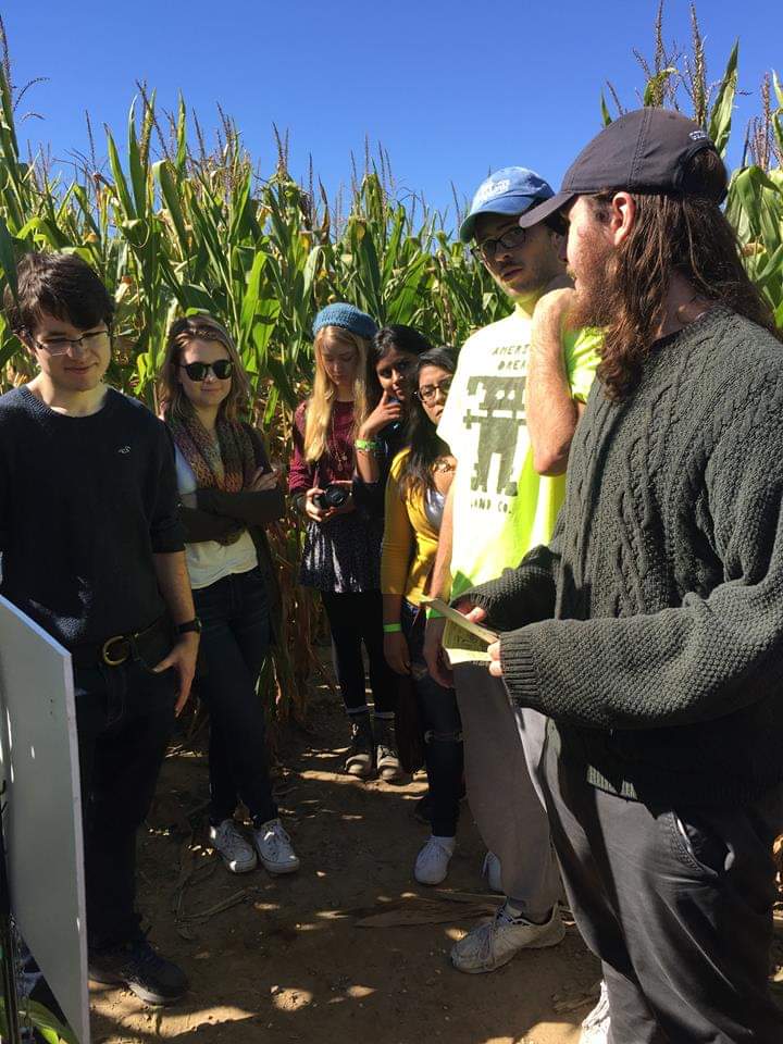 PRISM Math Club: A student presents the sign to students in a corn maze