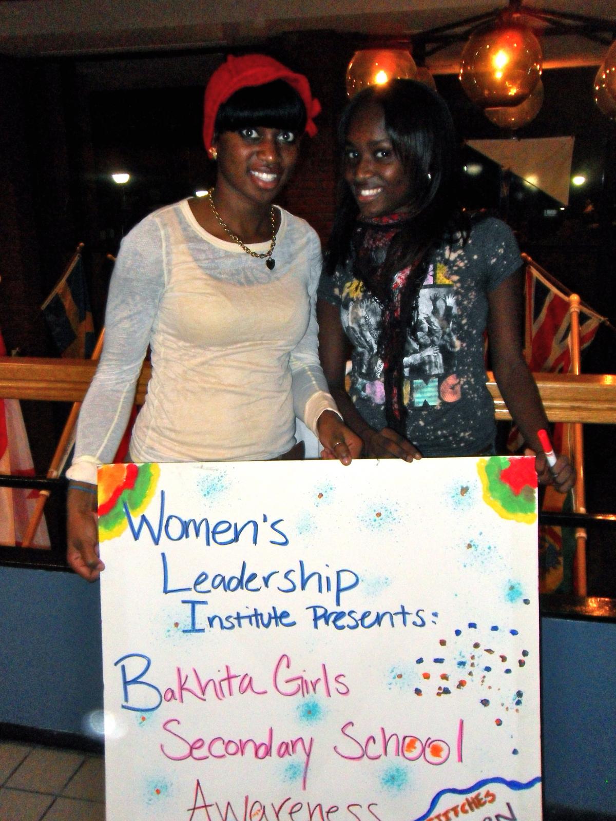 Two women holding women's leadership poster