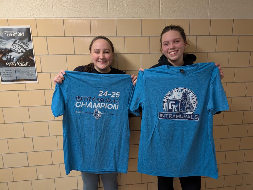 2 spikeball champions holding blue intramural t-shirts.