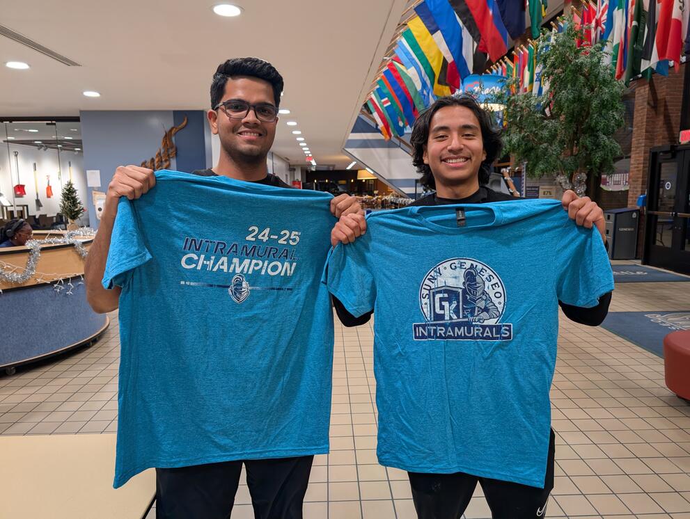 2 broomball champions holding blue intramural t-shirts.