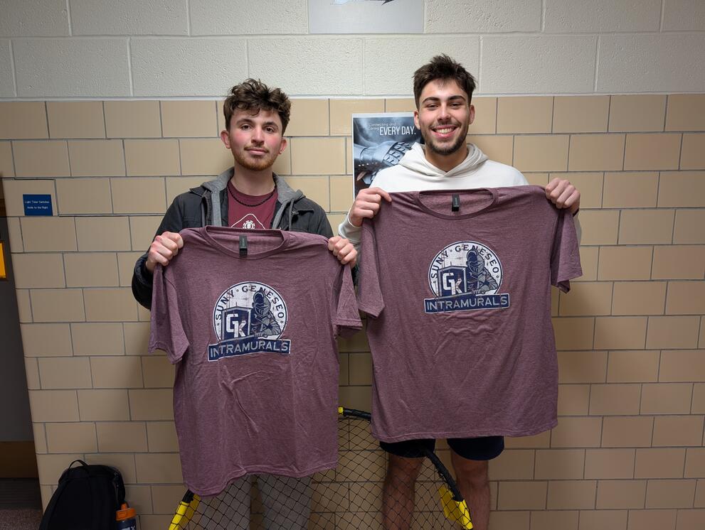 2 spikeball champions holding purple intramural t-shirts.