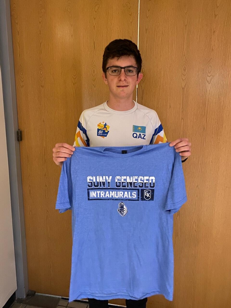 Ping pong champion holding a blue intramural shirt.