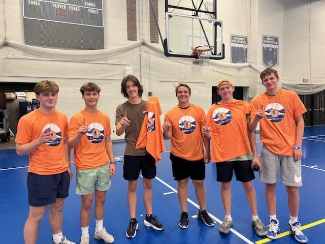 Six volleyball champions wearing orange uniforms