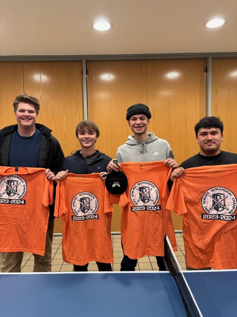 Four Ping Pong champions holding orange uniforms