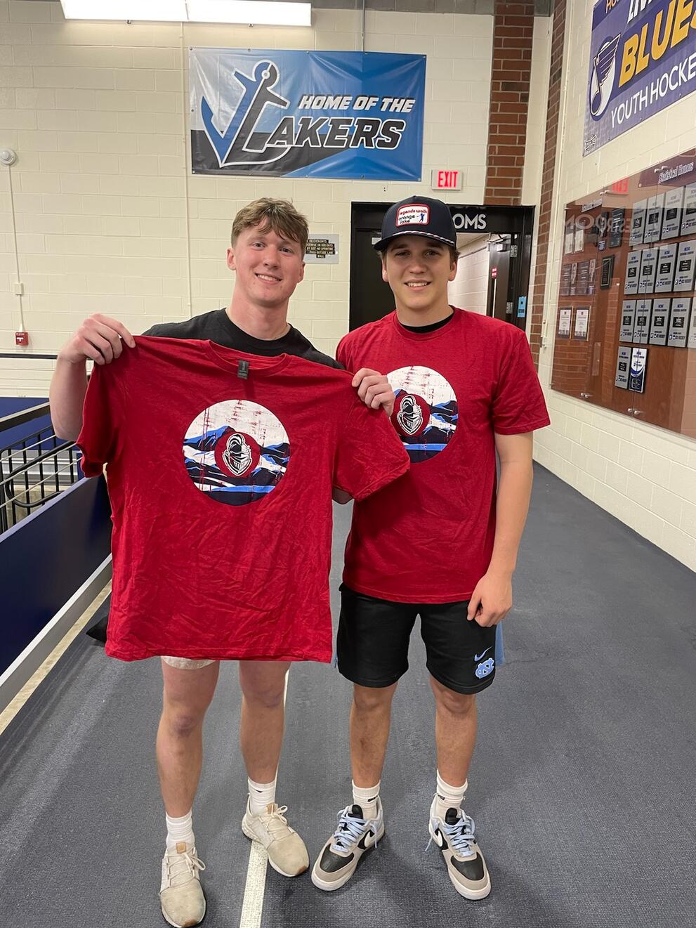 2 cornhole champions holding red intramural t-shirts.