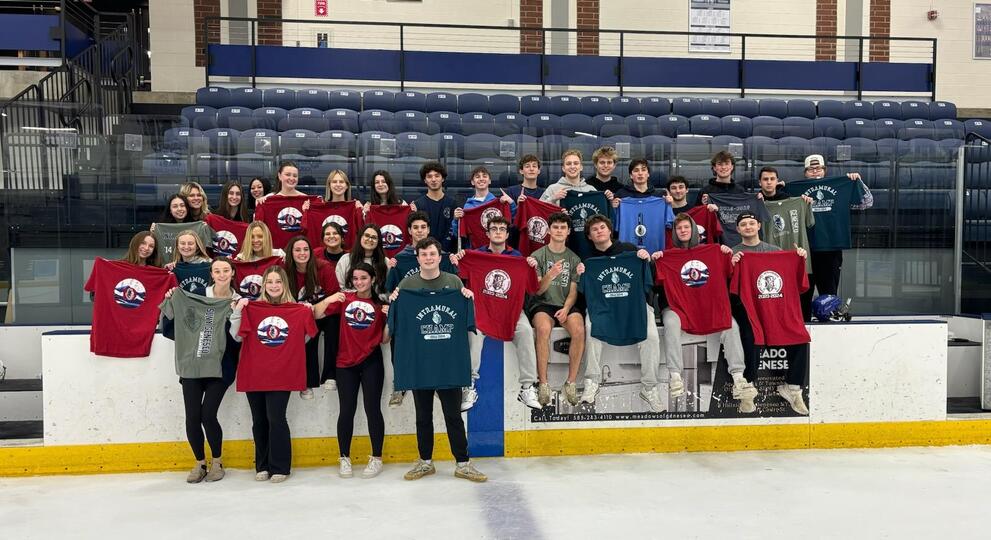 Group of broomball champions holding red, green, and gray intramural t-shirts.