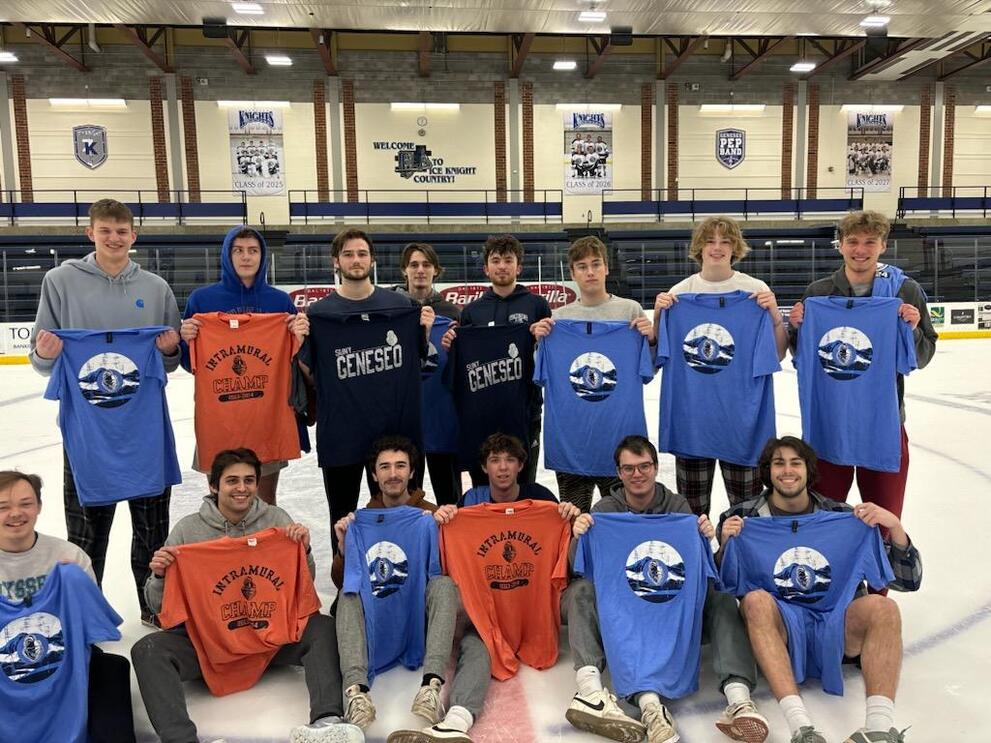 Group of broomball champions holding orange and blue intramural t-shirts.