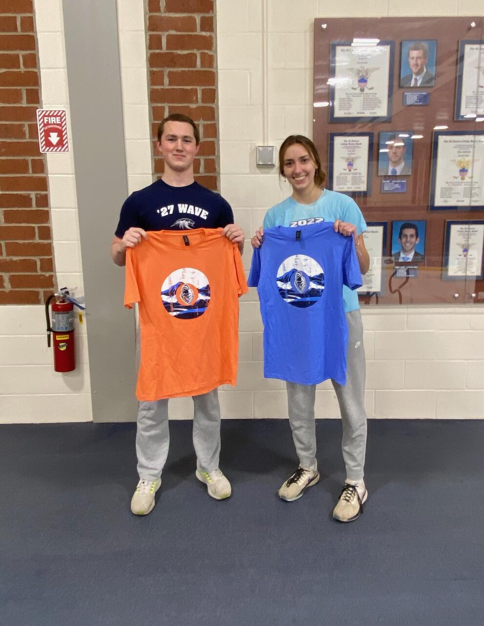 2 cornhole champions holding orange and blue intramural t-shirts.