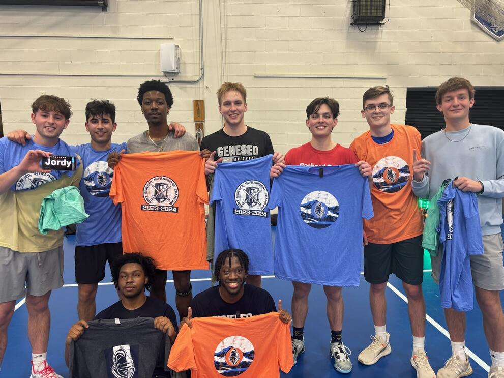 9 basketball champions holding orange and blue intramural t-shirts.