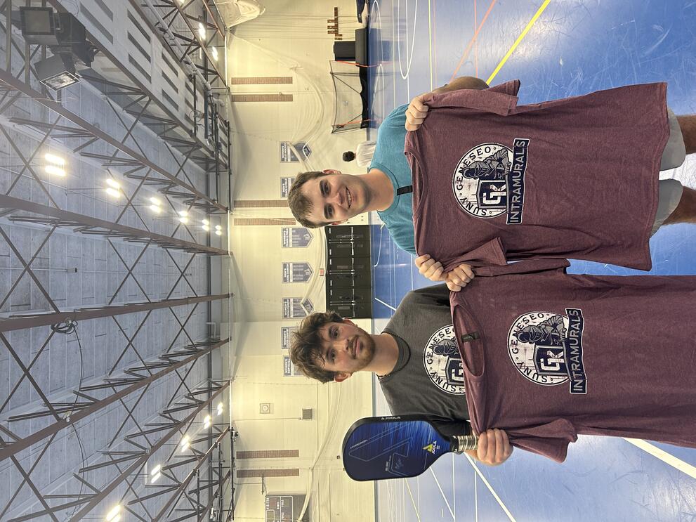 2 pickleball champions holding purple intramural t-shirts.