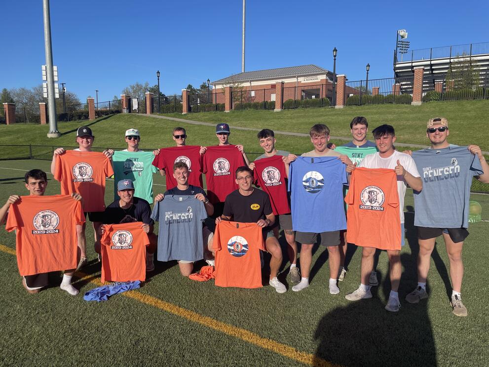 Group of kickball champions holding orange, red, and green intramural t-shirts.