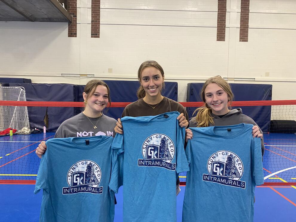 3 pickleball champions holding blue intramural t-shirts.
