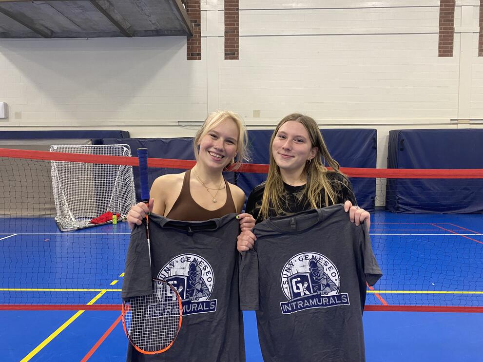 2 badminton champions holding black intramural t-shirts.