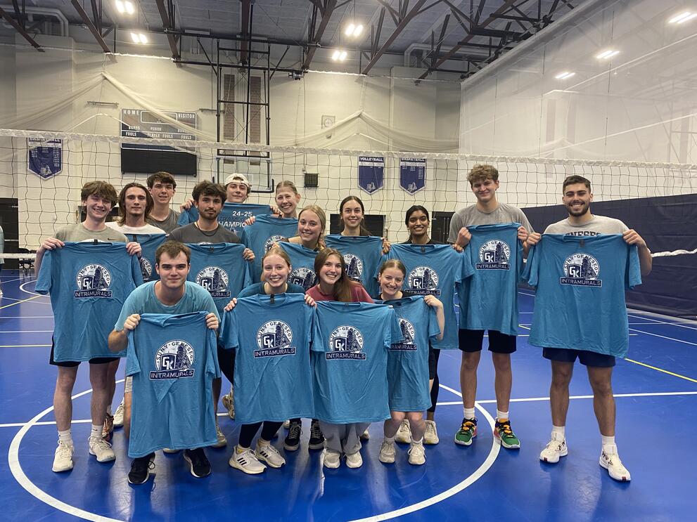 A large group of volleyball champions holding blue intramural t-shirts.