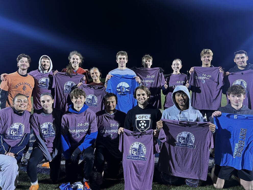 Large group of soccer champions holding purple intramural t-shirts.