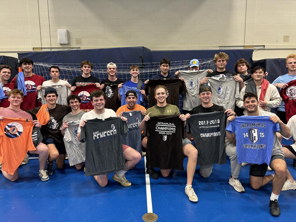 Group of soccer champions holding black, blue, and red intramural t-shirts.