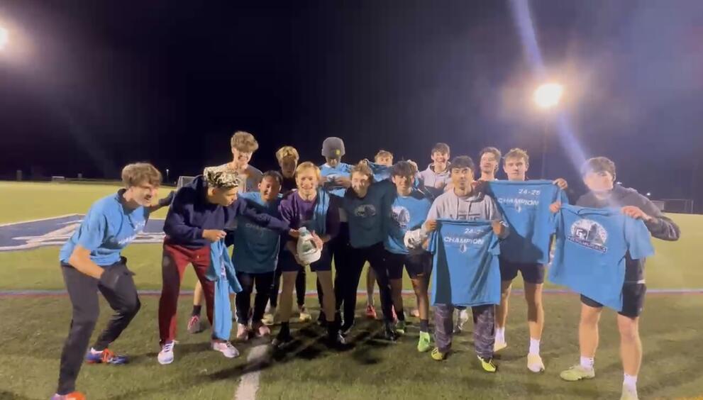 A large group of soccer champions holding blue intramural t-shirts.