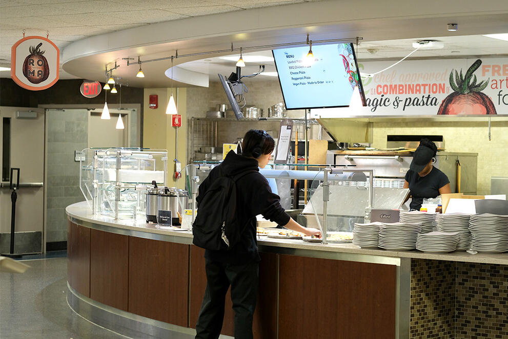 Student adds food to their plate at the Roma station in Letchworth Dining Complex.