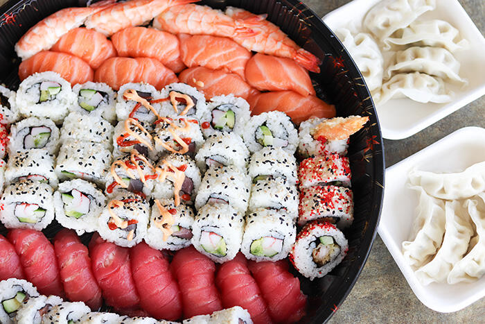 Assorted sushi dinner platter with steamed dumplings.