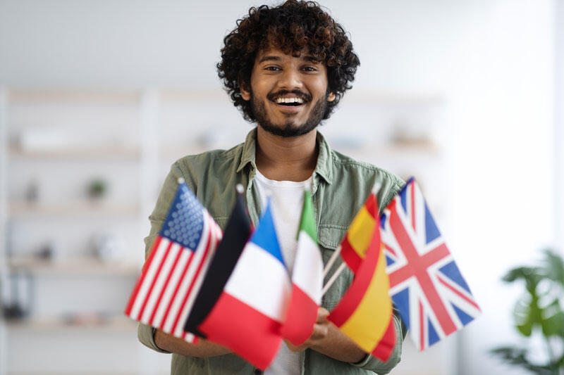Person holding small flags from various countries, including the U.S., France, Italy, Germany, Spain, and the U.K.