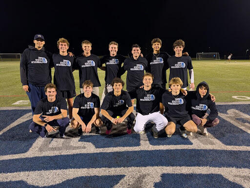 A group of people on a sports field at night wearing matching black “SUNY Geneseo Intramurals” T-shirts, posed together on a large logo.