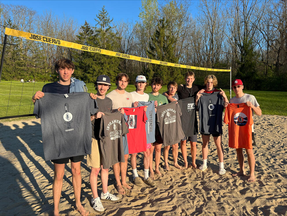 Group of sand volleyball champions holding gray intramural t-shirts.
