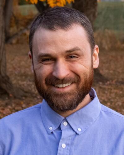 bearded man in blue button-up, smiling
