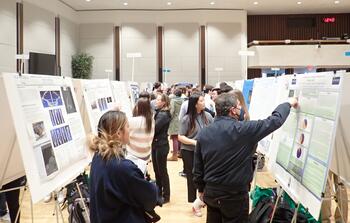 A group of people looking at posters of scientific research in the college Ballroom.