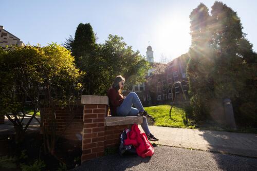 A student reads a book on a sunny spring day.