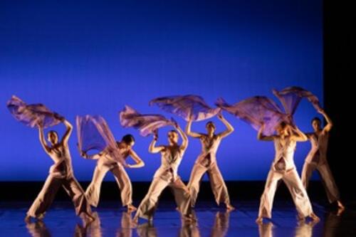 Members of the Geneseo Dance Ensemble perform against a blue background 