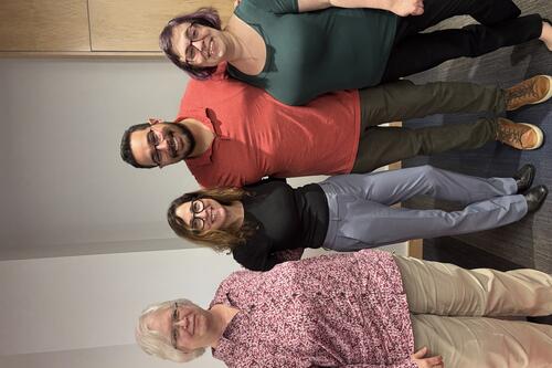 Four Sociology professors smiling and posing for a group photo indoors.