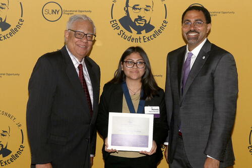 Michelly Meza-Benitez '23 standing with her award with the chancellor and others.