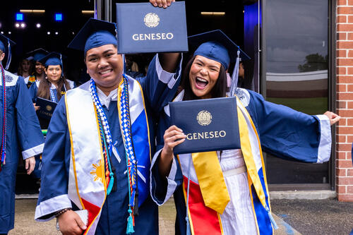 Two graduates show their diplomas after graduation. 