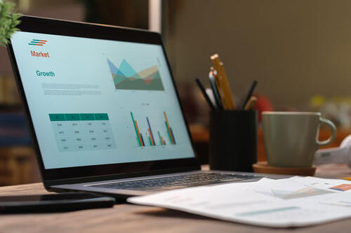 open laptop with charts and papers