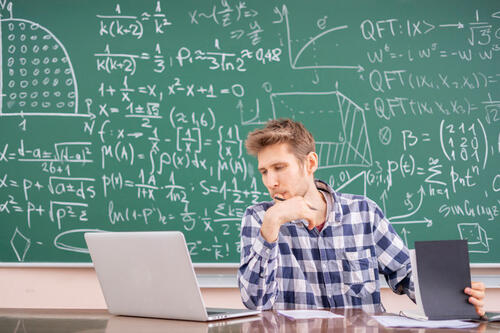 board covered with equations and man sitting with laptop