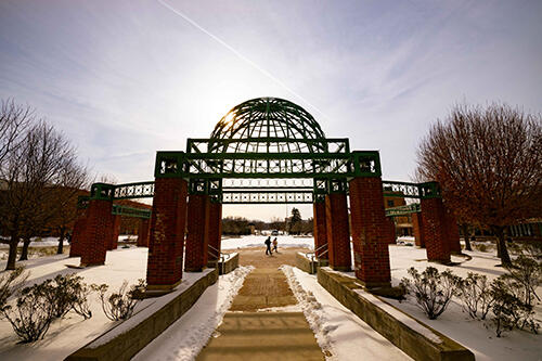 Students walk across the College Green walkway in winter.