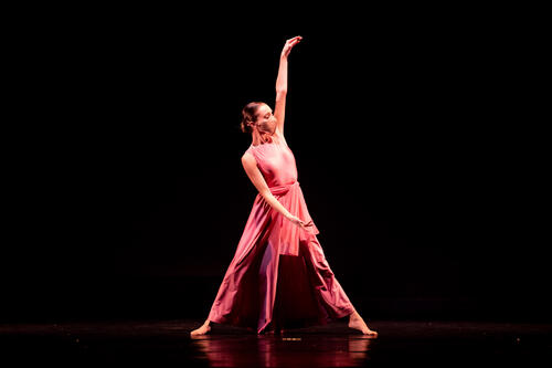 Jillian Johnson '22 dances in a rose-colored costume on stage.