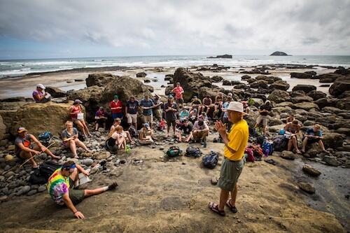 Professor talks to students on a beach in New Zealand.