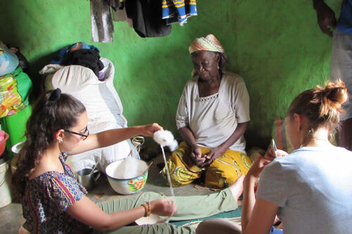 Two students learn to make thread in Ghana.