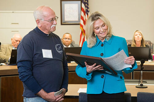 Tom Matthews and Connie Rocko look at the resolution in the Board of Supervisors meeting.