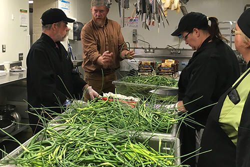 Dan DeZarn talks to CAS employees as they process garlic scapes in the kitchen.