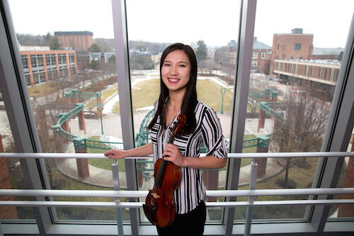 Evelyn Welch holding a violin in the Integrated Science Center.
