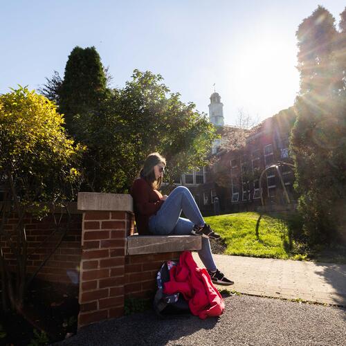 A student reads a book on a sunny spring day.