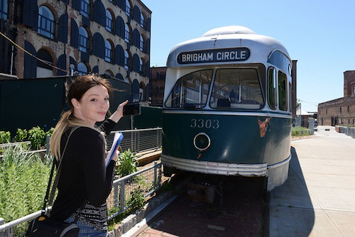 A student takes a photo of a former rail car that is now a relic