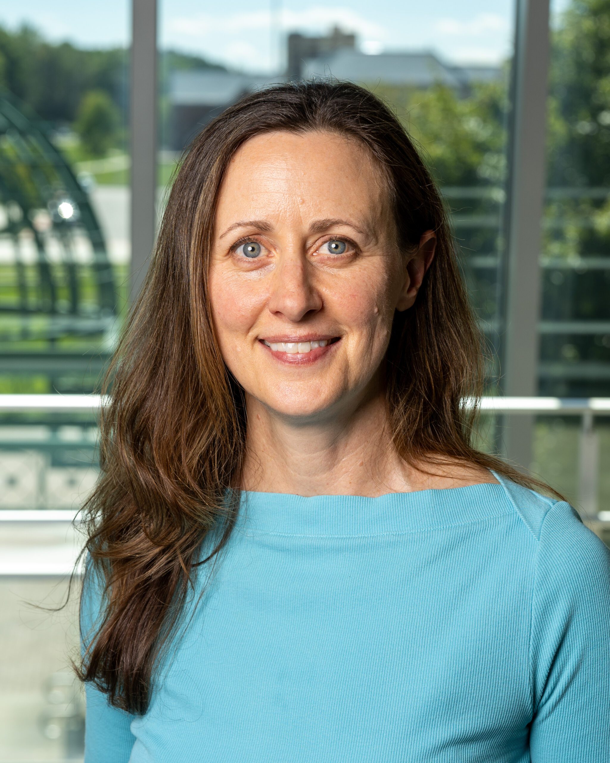 Dr. Hannam, Professor of Biology who is wearing a bright blue shirt, smiles into the camera