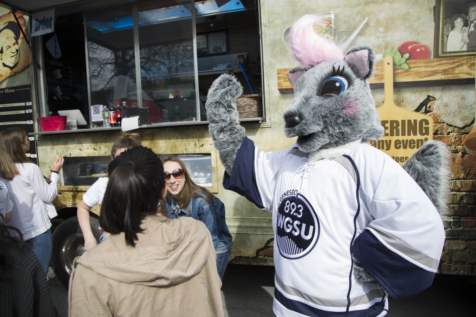Genny giving out high fives to students by a food truck.