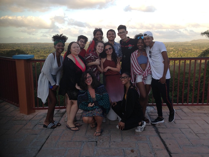 A group of friends smiling and posing together at sunset with a scenic landscape view in the background. A group of friends smiling and posing together at sunset with a scenic landscape view in the background.